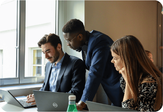 Drie mensen rond een bureau die naar een computer kijken